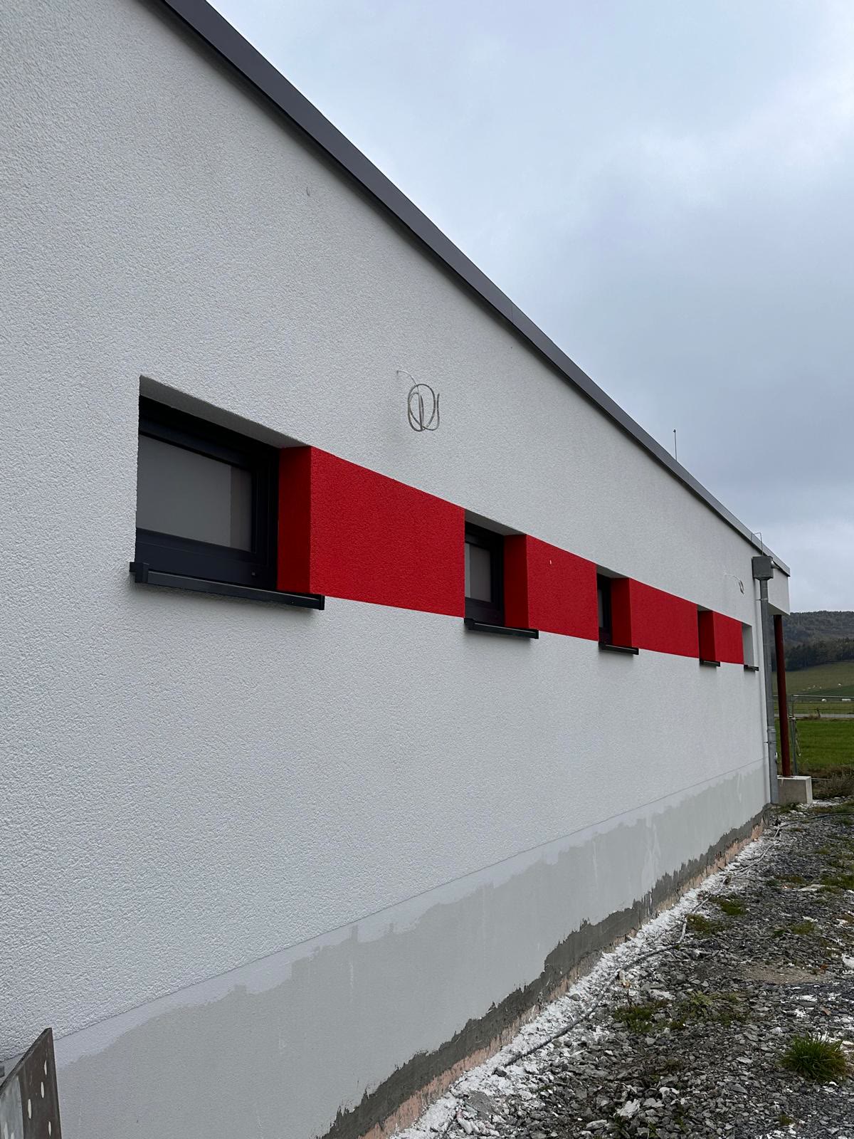 Hell verputzte Fassade mit roter Akzentfläche – Neubau in Sundern